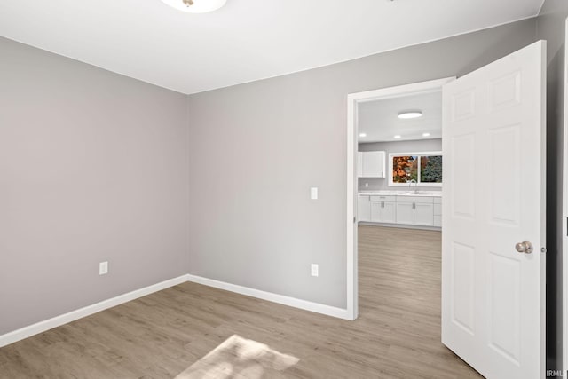 spare room featuring sink and light hardwood / wood-style floors