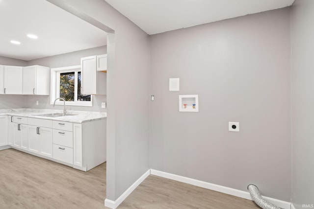 laundry room featuring hookup for a washing machine, electric dryer hookup, sink, and light wood-type flooring