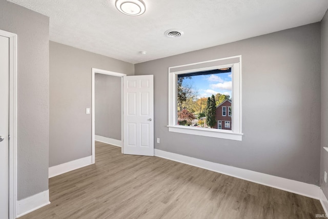 unfurnished bedroom with a textured ceiling and light hardwood / wood-style flooring