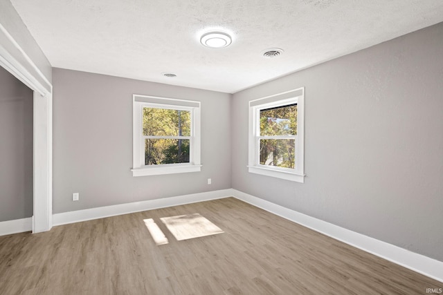 unfurnished room featuring light hardwood / wood-style flooring and a textured ceiling