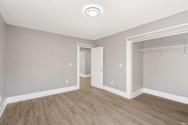 unfurnished bedroom featuring a closet, hardwood / wood-style flooring, and a textured ceiling