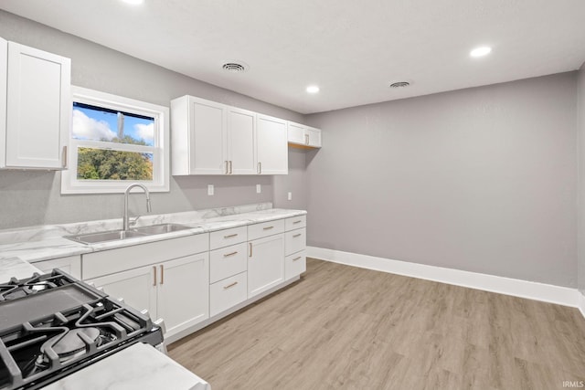 kitchen featuring sink, light hardwood / wood-style floors, white cabinetry, and range with gas cooktop