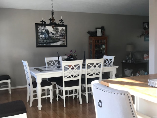 dining area with dark hardwood / wood-style floors and an inviting chandelier