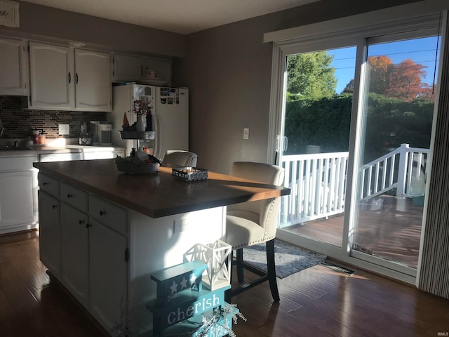 kitchen featuring backsplash, a center island, white fridge, and dark wood-type flooring