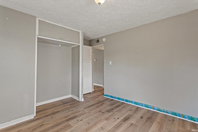 unfurnished bedroom with a closet, a textured ceiling, and wood-type flooring