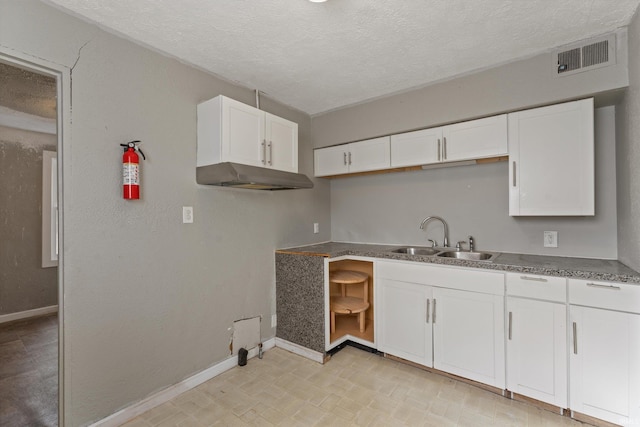 kitchen featuring a textured ceiling, sink, and white cabinets