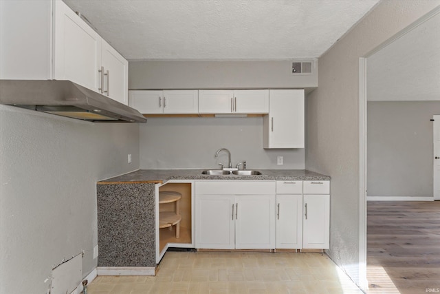 kitchen featuring white cabinetry, light hardwood / wood-style flooring, a textured ceiling, and sink