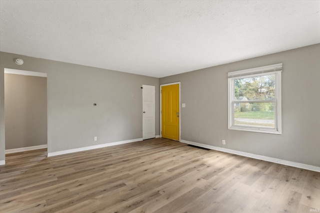 unfurnished room with a textured ceiling and light wood-type flooring