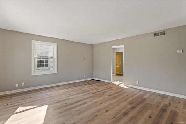 spare room featuring a textured ceiling and light wood-type flooring