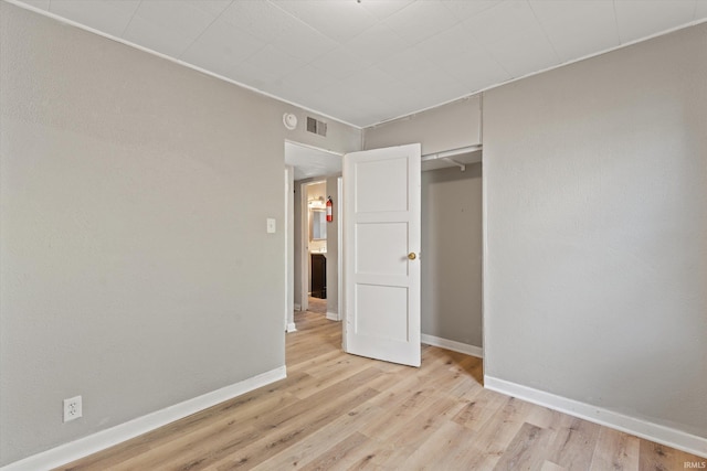 unfurnished bedroom with a closet and light hardwood / wood-style floors