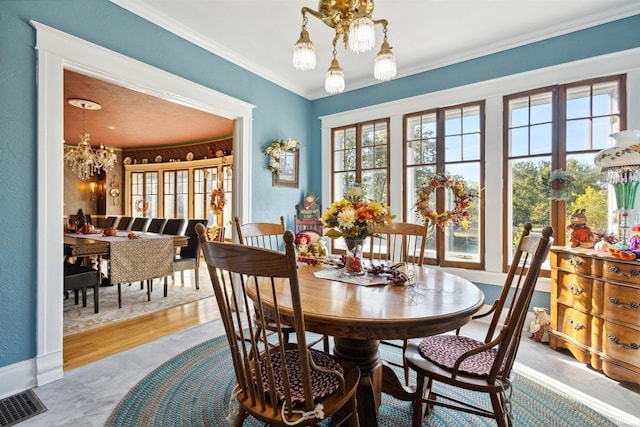 dining room with a notable chandelier, crown molding, visible vents, baseboards, and wood finished floors