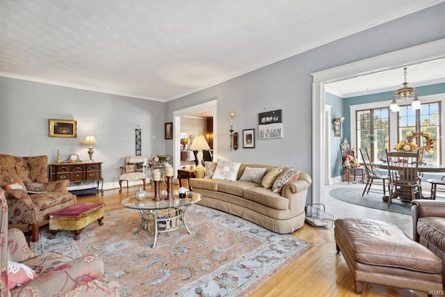 living room with a notable chandelier, light hardwood / wood-style floors, and crown molding