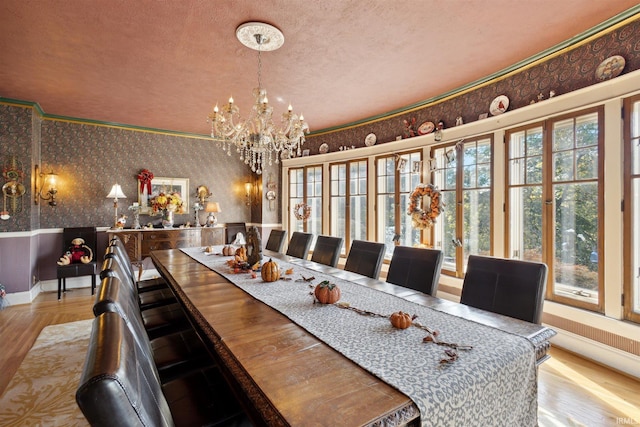 dining space with light hardwood / wood-style floors, a textured ceiling, an inviting chandelier, and plenty of natural light