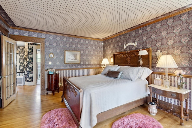 bedroom featuring wood finished floors, crown molding, and wallpapered walls