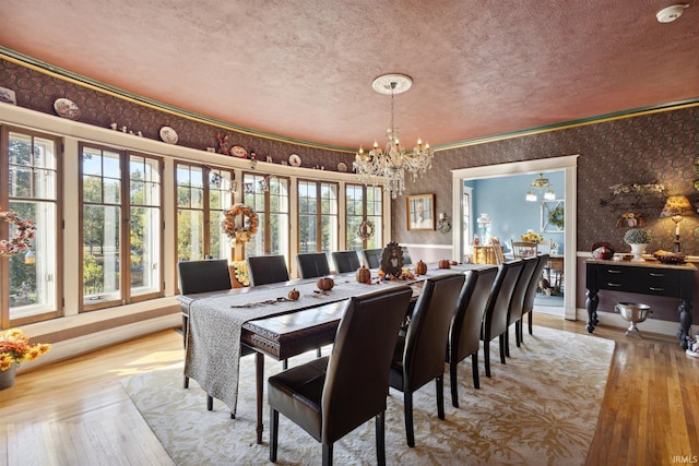 dining space with light hardwood / wood-style floors, a notable chandelier, and a textured ceiling