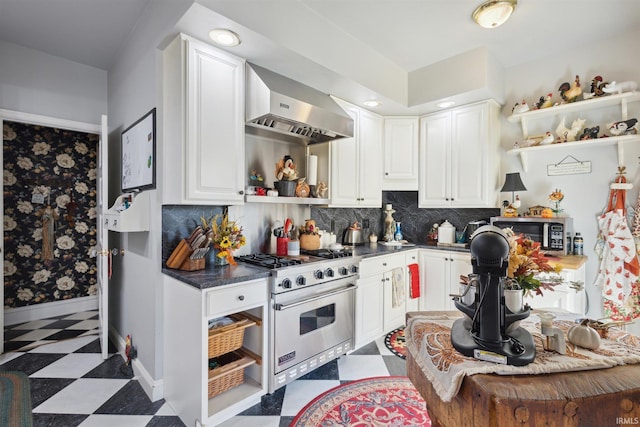 kitchen featuring backsplash, appliances with stainless steel finishes, wall chimney range hood, and white cabinetry