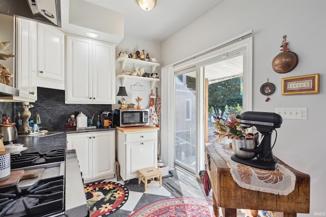 kitchen with range with gas stovetop, sink, white cabinets, and backsplash