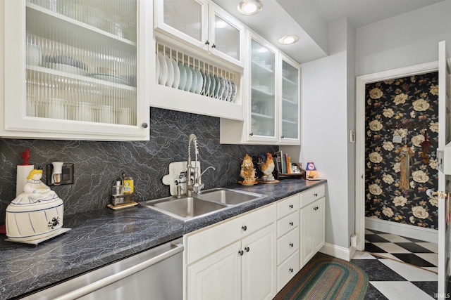 kitchen featuring stainless steel dishwasher, white cabinets, sink, and backsplash