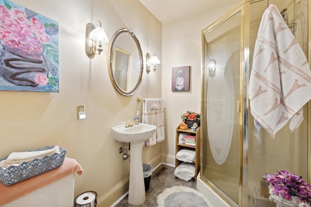 bathroom with toilet, a shower stall, and baseboards