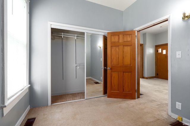 unfurnished bedroom featuring a closet and light colored carpet