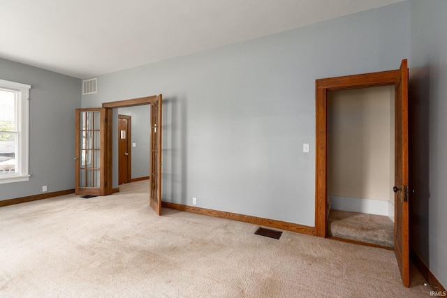 carpeted spare room featuring french doors