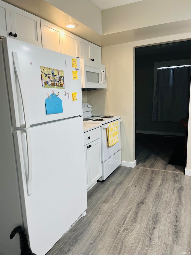 kitchen featuring white appliances, light hardwood / wood-style flooring, and white cabinets