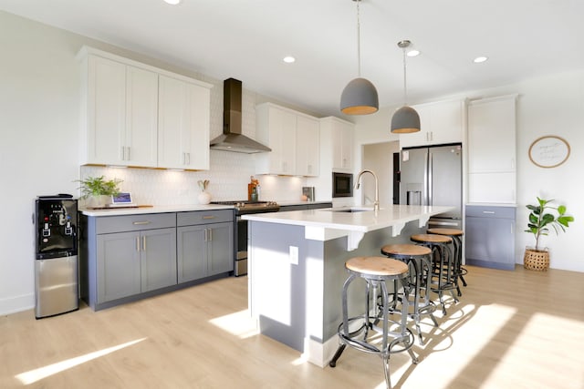 kitchen featuring white cabinetry, wall chimney exhaust hood, appliances with stainless steel finishes, and gray cabinets