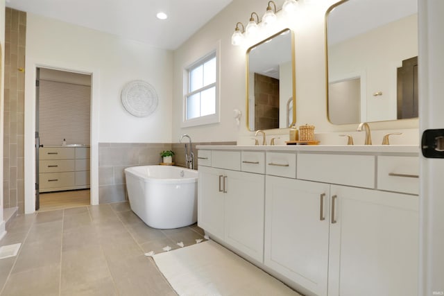 bathroom with vanity, tile patterned floors, tile walls, and a bath