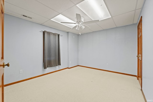 empty room with a paneled ceiling, carpet flooring, and ceiling fan