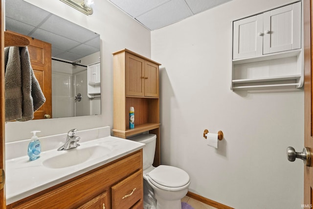 bathroom with vanity, toilet, a shower, and a paneled ceiling