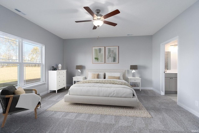 carpeted bedroom with ensuite bath and ceiling fan