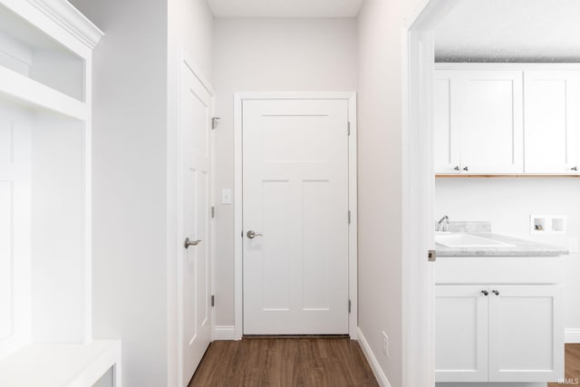 interior space featuring hookup for a washing machine, sink, a textured ceiling, cabinets, and dark hardwood / wood-style floors