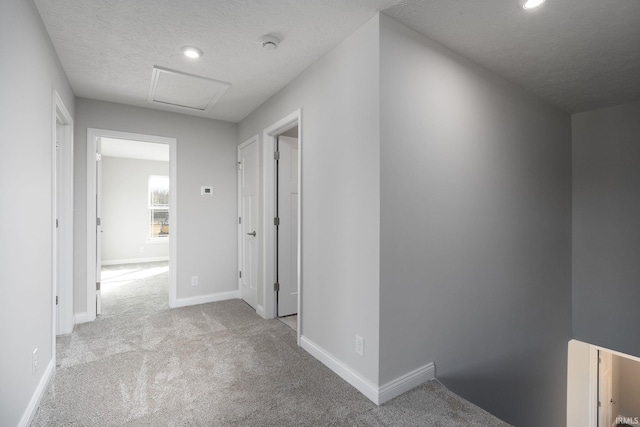 hall with a textured ceiling and light colored carpet