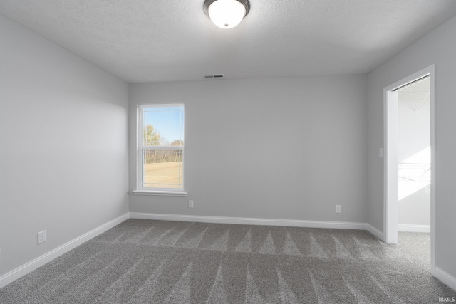 spare room with dark carpet and a textured ceiling