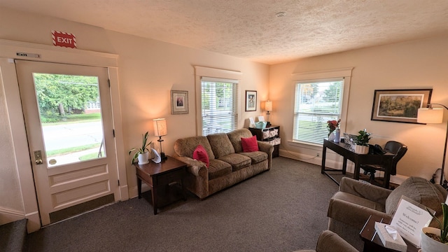 living room featuring a textured ceiling, a wealth of natural light, and dark colored carpet