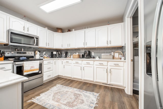 kitchen featuring white cabinets, stainless steel appliances, dark wood-type flooring, and backsplash