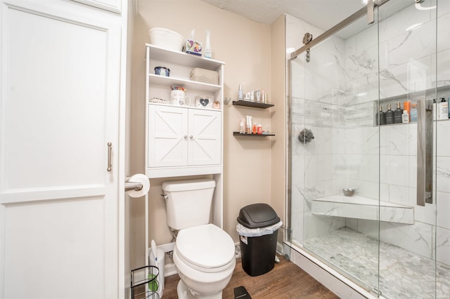 bathroom featuring a shower with shower door, hardwood / wood-style flooring, and toilet