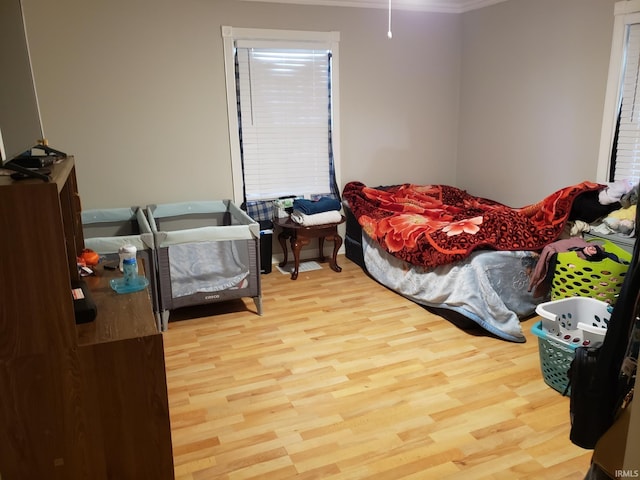 bedroom with crown molding and light wood-type flooring