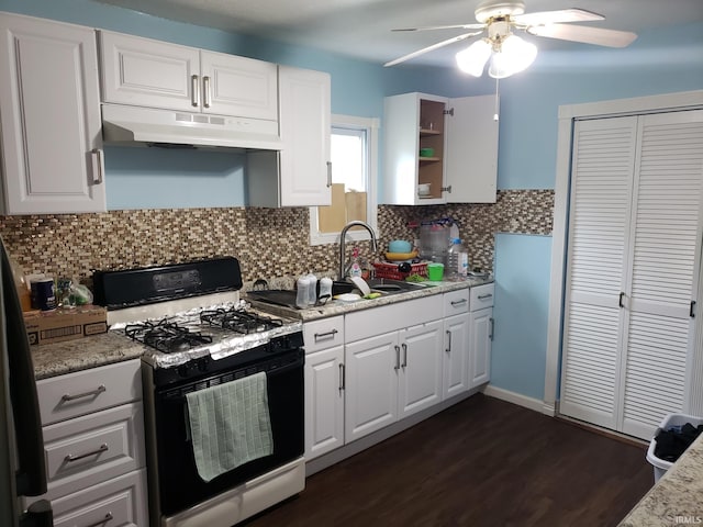 kitchen with decorative backsplash, dark wood-type flooring, gas range gas stove, sink, and white cabinetry