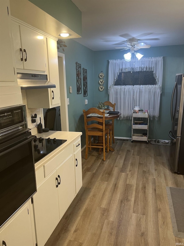 4116 N Lancaster Dr, Muncie, IN 47304 - kitchen with ceiling fan, wood finished floors, black appliances, under cabinet range hood, and white cabinetry