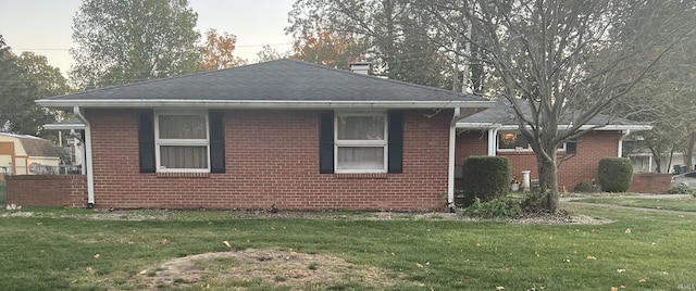 4116 N Lancaster Dr, Muncie, IN 47304 - view of side of property with a yard, brick siding, a shingled roof, and a chimney