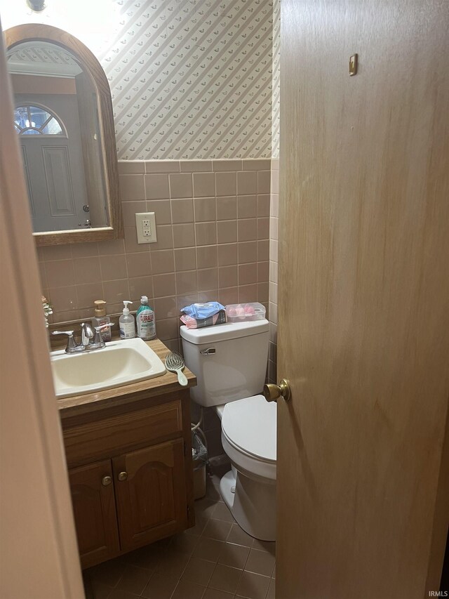 4116 N Lancaster Dr, Muncie, IN 47304 - half bath with tile walls, vanity, tile patterned floors, toilet, and wallpapered walls