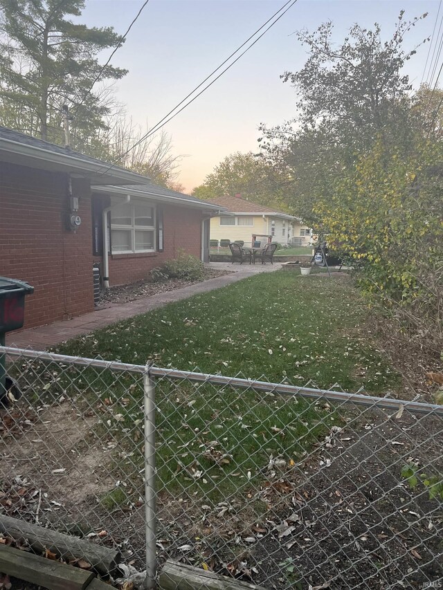 4116 N Lancaster Dr, Muncie, IN 47304 - view of side of home featuring a yard, brick siding, and fence