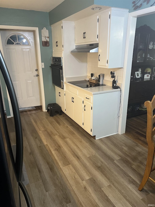 4116 N Lancaster Dr, Muncie, IN 47304 - kitchen with white cabinets, dark wood finished floors, tasteful backsplash, under cabinet range hood, and black appliances