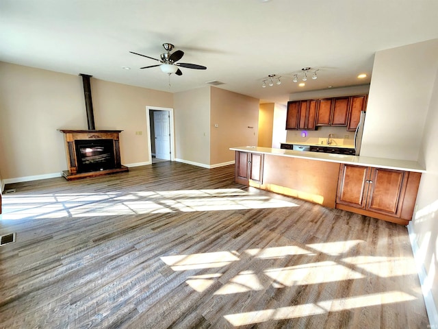 kitchen with sink, a wood stove, ceiling fan, stainless steel refrigerator, and light hardwood / wood-style flooring