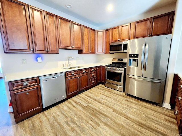 kitchen featuring appliances with stainless steel finishes, sink, and light hardwood / wood-style floors