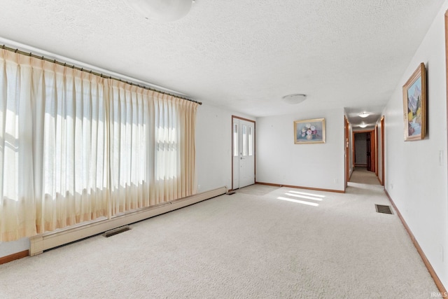 carpeted empty room with baseboard heating and a textured ceiling