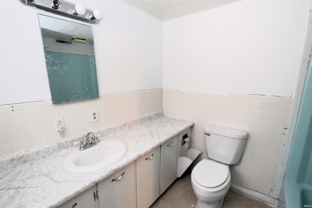 bathroom featuring a tub, vanity, toilet, and tile walls