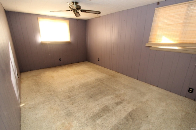 unfurnished room featuring ceiling fan, wooden walls, and carpet floors