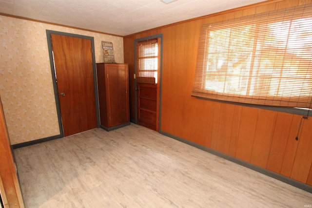 unfurnished room with light hardwood / wood-style floors and wooden walls